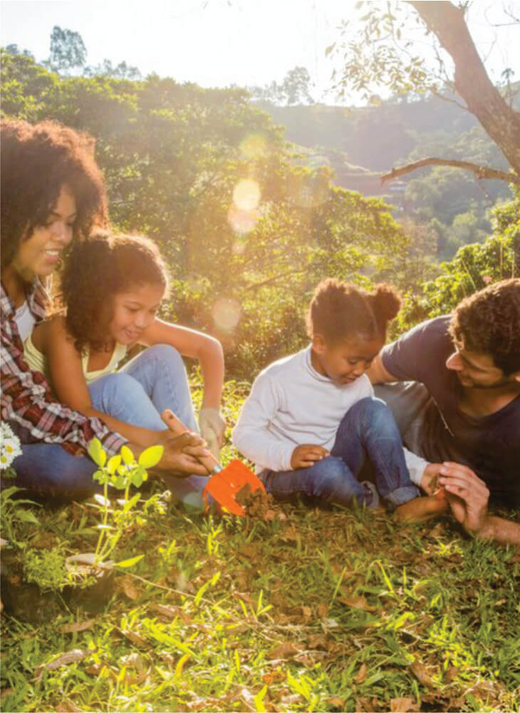 father, mother, and two kids sitting on green grass near trees and sharing activities together on 10-Day Kenya & Tanzania safari with kids