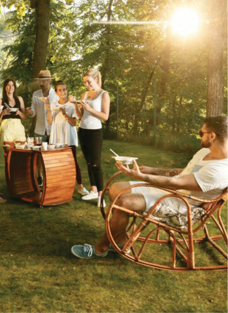 five people having dinner together while standing and sitting on wooden chairs outdoors on Kenya & Tanzania safari on a budget