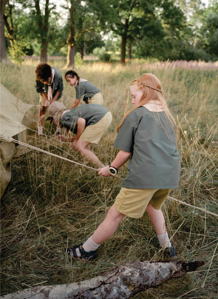 group of kids in school uniform pitching and taking down a tent onto flat grass in Masai Mara on 3 days Masai Mara budget camping safari