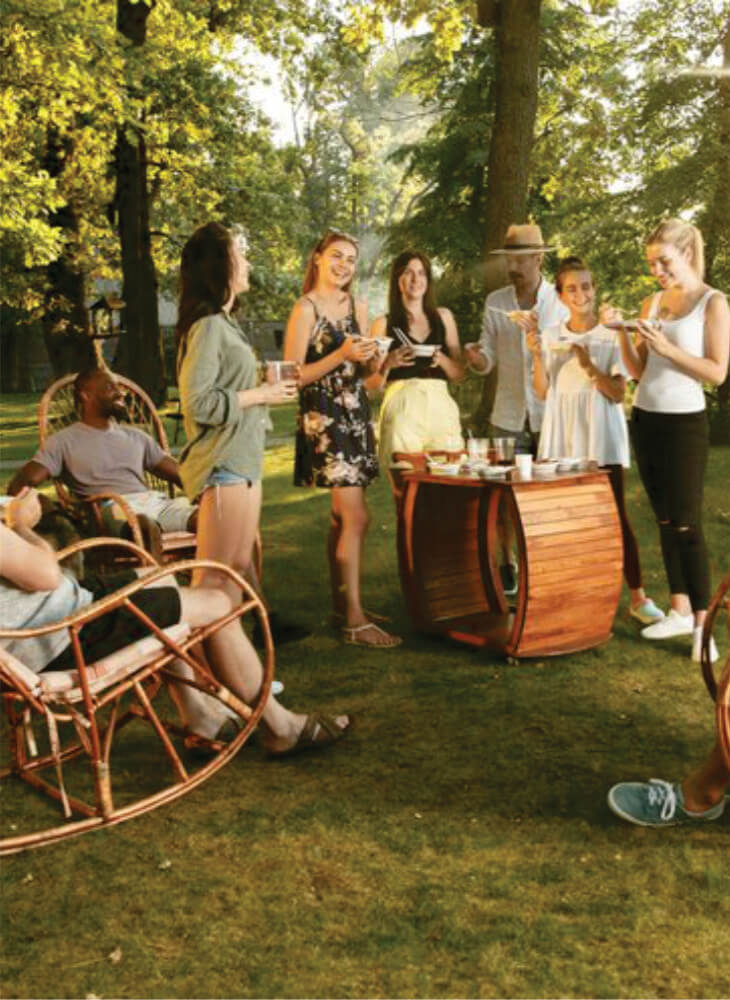 group of people having dinner together while sitting on rustic wooden chairs outdoors on Kenya & Tanzania safari on a budget