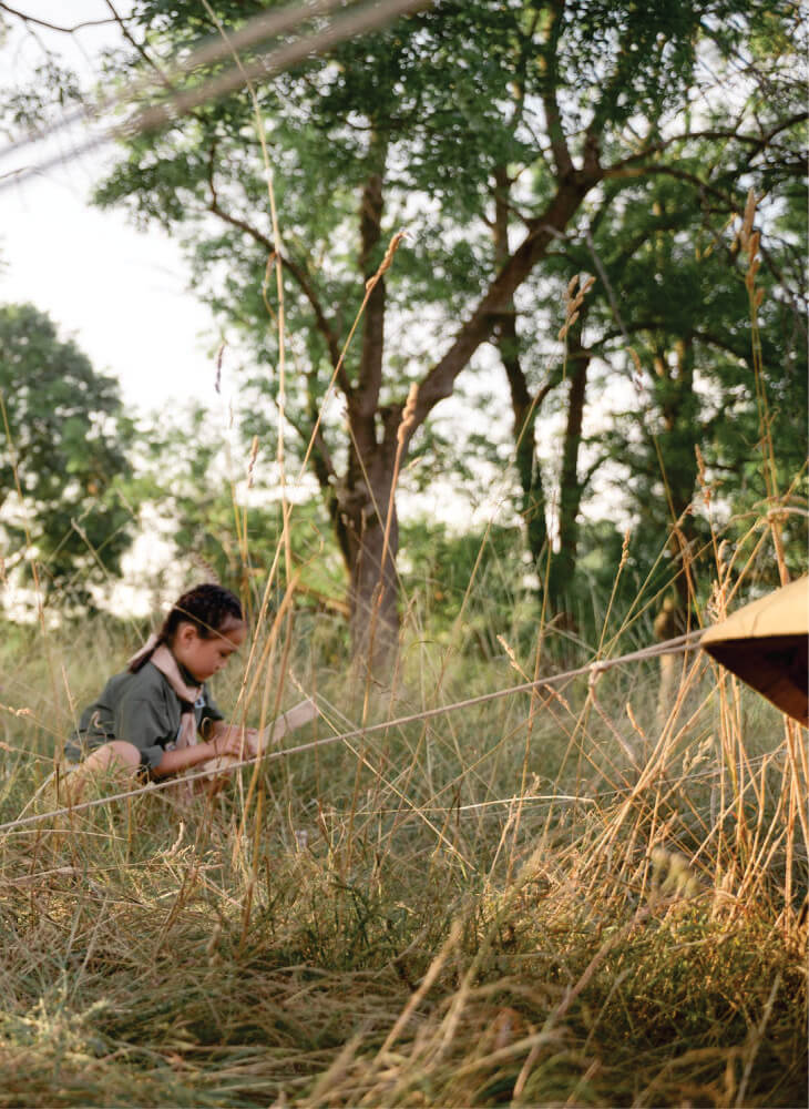 kid in school uniform pitching a tent onto flat grass in Masai Mara on 3 days Masai Mara budget camping safari