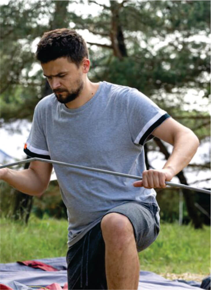 man preparing to pitch his tent on ground near trees in Masai Mara on affordable Masai Mara camping safaris in Kenya