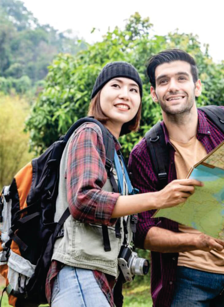 two friends holding drawing map and standing near trees on affordable 5-day Masai Mara and Lake Nakuru safari tour