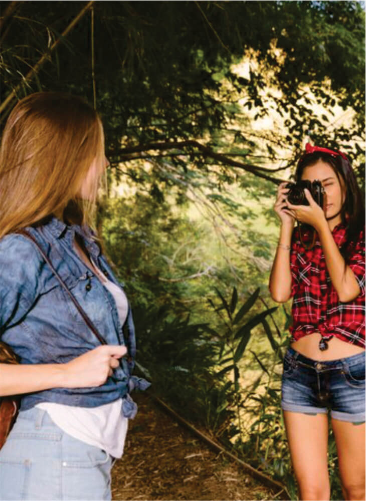 Two women with brown backpacks standing and taking photos in Masai Mara on affordable safari to Serengeti and Masai Mara