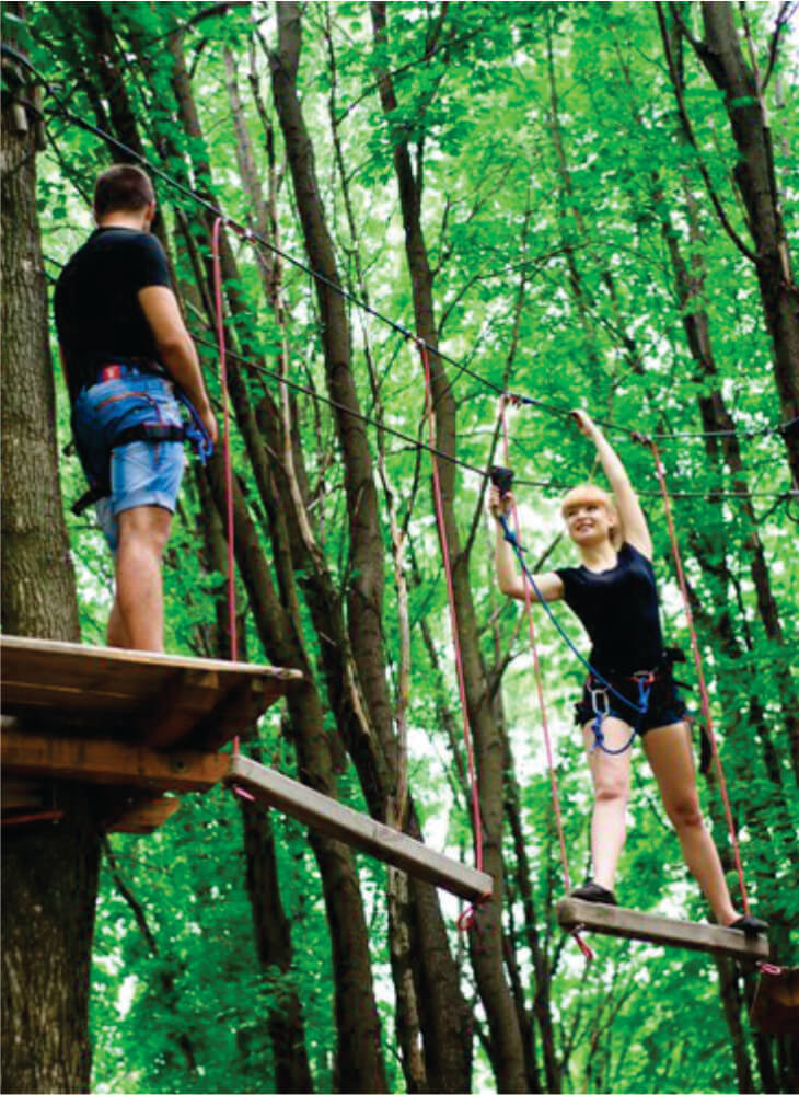 two young people walking on the rope path in the air in an adventure park in Kenya on adventure camping safaris