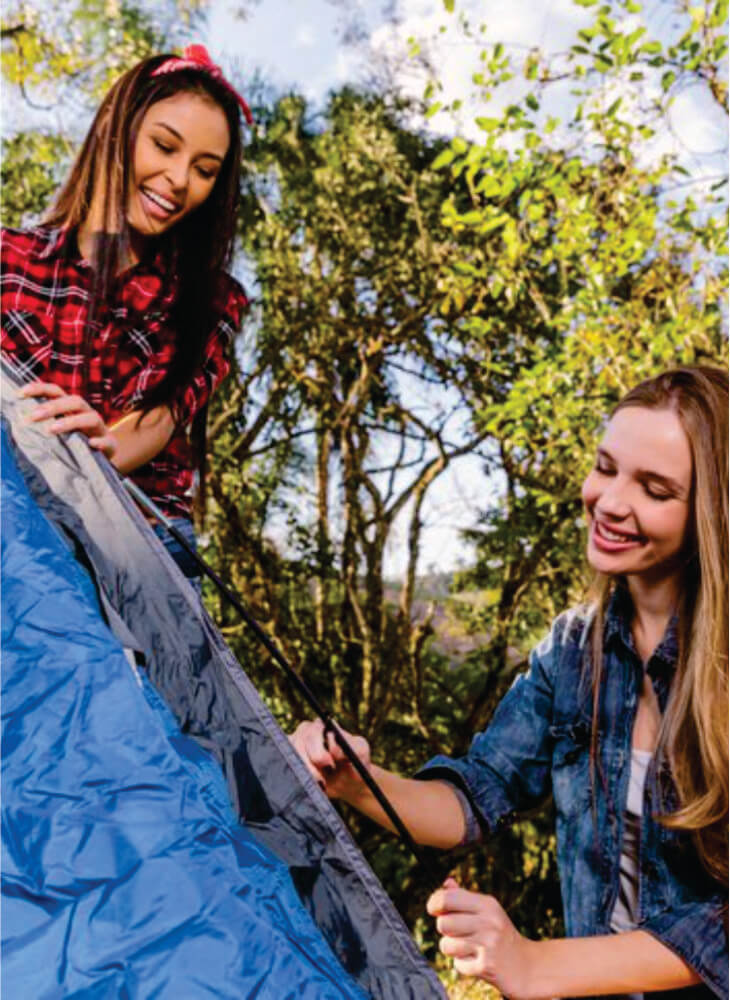 Two young women pitching a blue tent in Masai Mara on African safari to Serengeti and Masai Mara