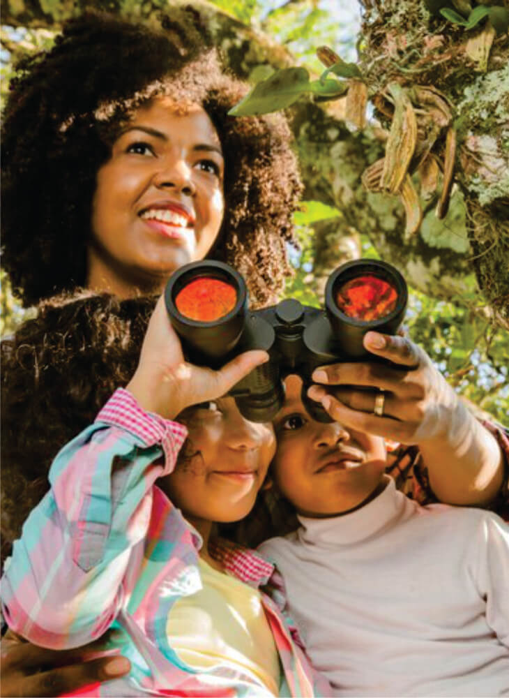 woman and two kids looking through binoculars in daytime in Masai Mara on African safari for family