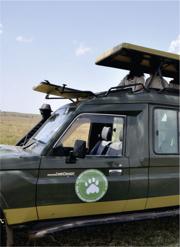 three travelers enjoying views from a pop up top of a green jeep with Bon Voyage Budget Safari in Kenya logo on 3 days jeep tour
