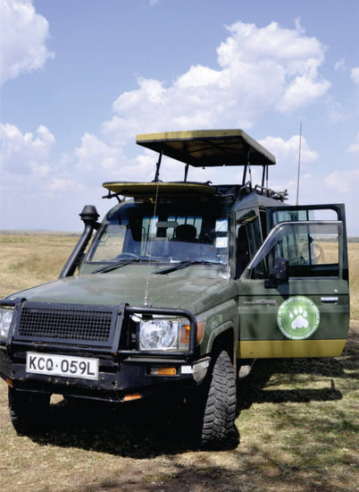 a green 4x4 jeep parked on green grass field with pop up roof and front doors open in Masai Mara at daytime on a jeep tour
