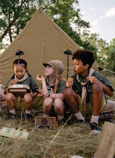 four kids in school uniform sitting near brown tent in Masai Mara, enjoying special moments together on Masai Mara budget camping safaris in Kenya