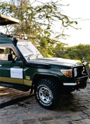 front part of custom-built 4x4 green jeep with suspension and pop-up-top roof parked in Amboseli on Amboseli safari jeep tours