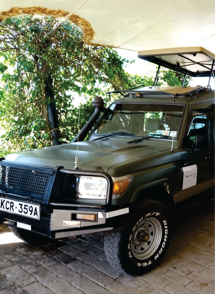 front view of custom-built 4x4 green jeep with pop-up-top roof parked near hotel Amboseli on private jeep safari tour in Kenya