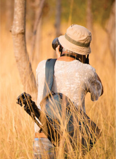 male tourist backpacker taking photo near trees in Masai Mara on 6-day Masai Mara Amboseli safari tours