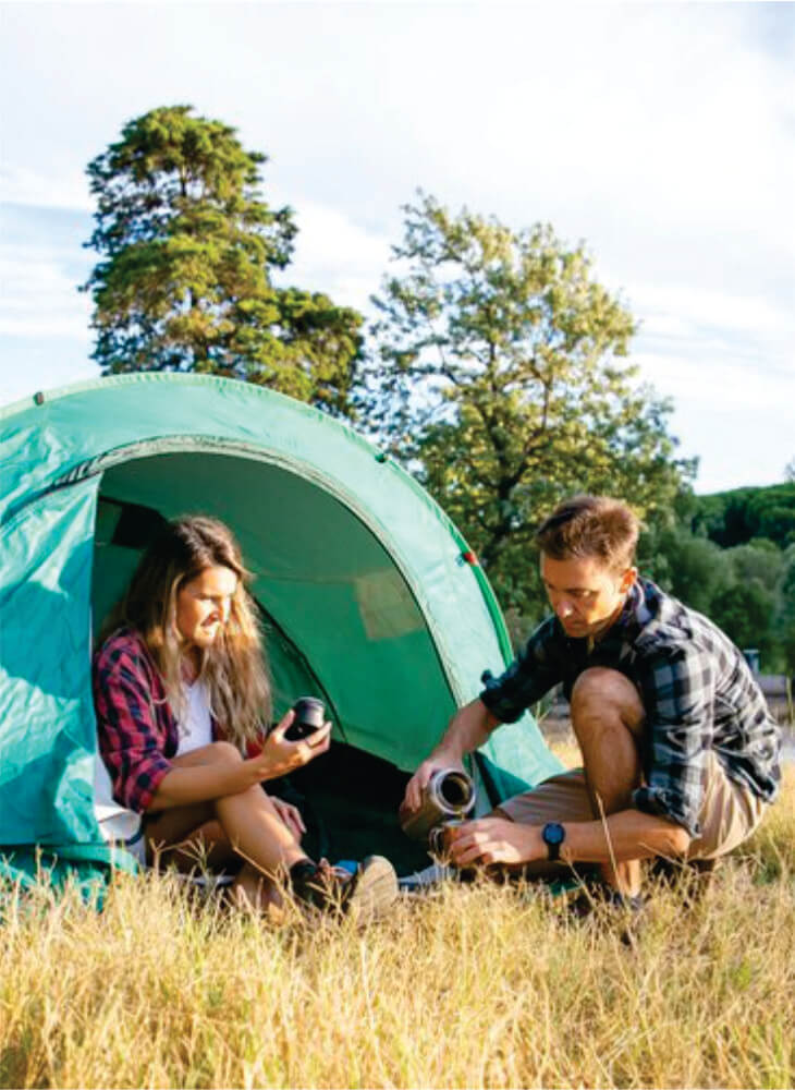 two people sitting near the campsite tent near trees in Masai Mara and preparing tea on Kenya camping safari tour