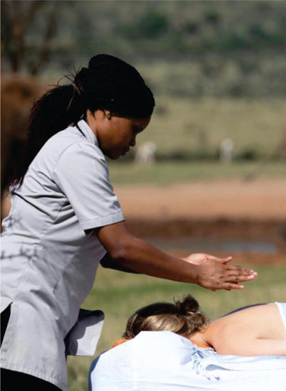 young masseuse giving an attractive woman back massage in an open field in Masai Mara on Masai Mara Sopa Lodge Safari tour
