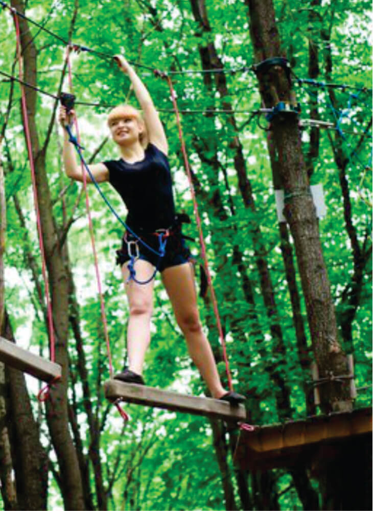 young woman walking on the rope path in the air in an adventure park in Kenya on an affordable Kenya adventure safari tour